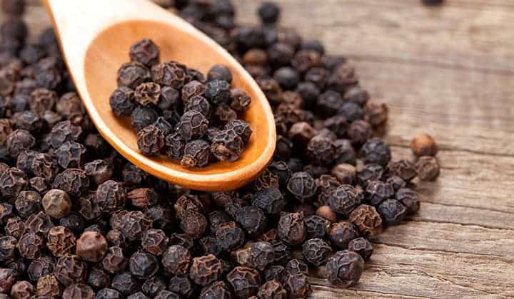 Black peppercorns on a wooden surface