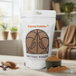 Sattvic Foods cacao powder package on a wooden table with cacao powder and a scoop.