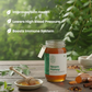 Jar of Neem Honey with honey dipper and ingredients on a wooden surface with greenery in the background.