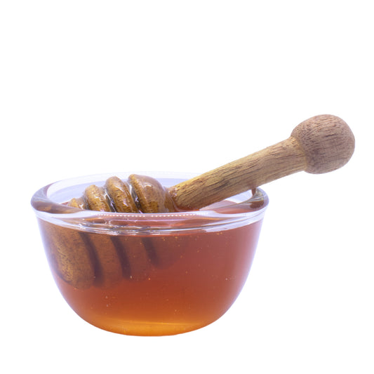 Neem honey in a glass bowl with a honey dripper