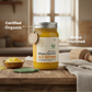 Jar of Organic Bilana Churned A2 Ghee on a wooden surface with a blurred kitchen background.